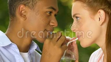 多民族年轻夫妇喝着吸管饮料，带着爱，约会
